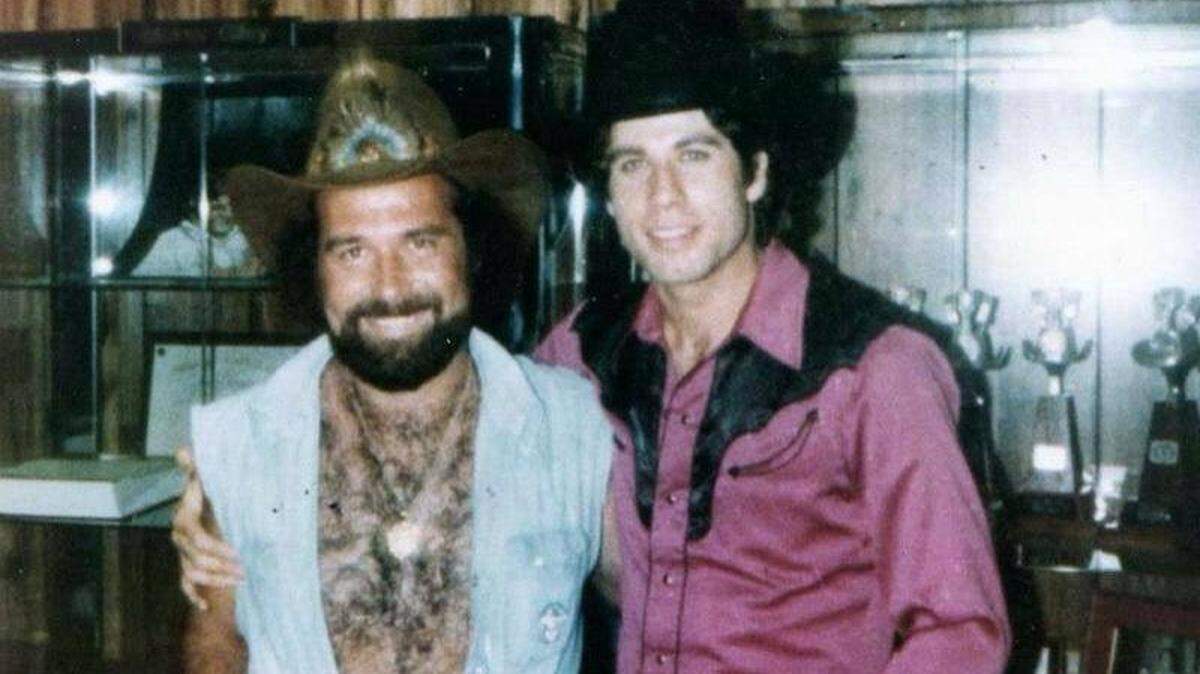 Country singer Johnny Lee visits with John Travolta on the set of the 1980 film “Urban Cowboy.” Lee’s hit song “Looking For Love” was written by two school teachers from the Coast.