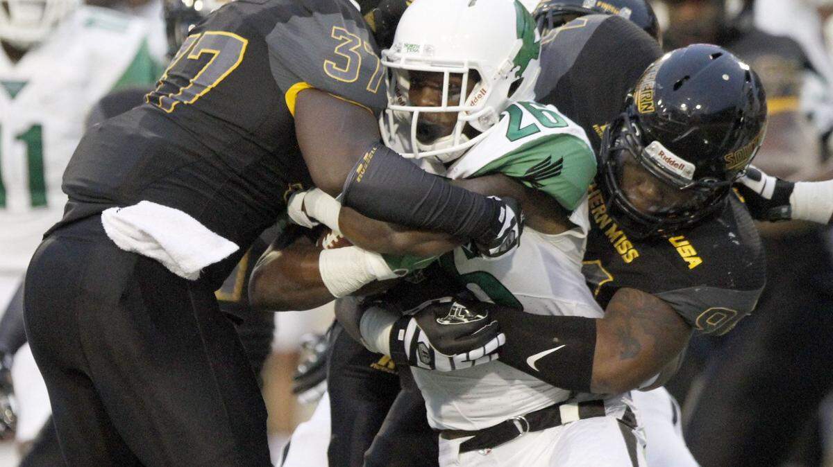 TIM ISBELL/SUN HERALD 
 North Texas running back Jeffrey Wilson is brought down by Southern Miss defenders Dylan Bradley and Sherrod Ruff, Saturday, Oct. 3, 2015.