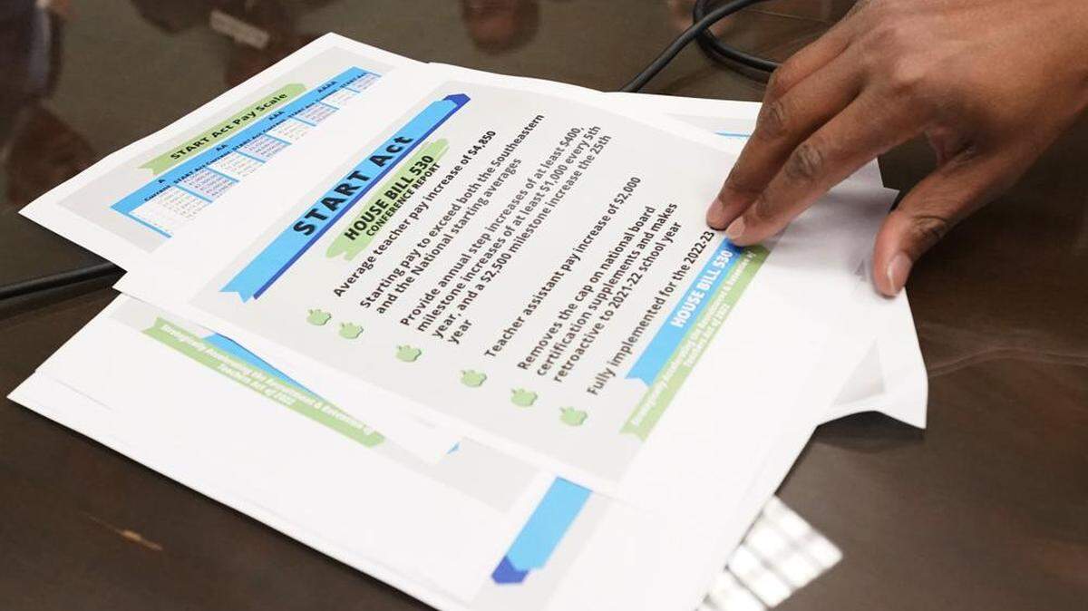 A reporter reaches for a sheet outlining the salient points of a teacher pay raise conference report during a news conference called by Speaker Philip Gunn, R-Clinton, during which he and several House leaders said the body had signed off on a plan to increase some of the lowest teacher salaries in the nation by an average of $4,850, at the Mississippi Capitol in Jackson, Miss., Thursday, March 10, 2022. The bill now goes to the Senate for consideration. (AP Photo/Rogelio V. Solis)
