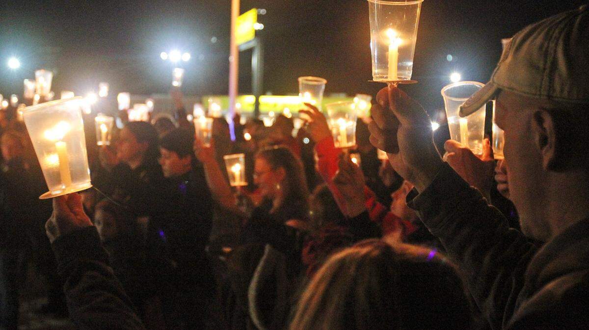 JOHN FITZHUGH/SUN HERALD/FILE 
 Jason Rife, right, of Vancleave, right, holds a candle in memory of his slain friend, Waffle House server Julie Brightwell, during a memorial service for her on the beach in Biloxi on Dec. 4.