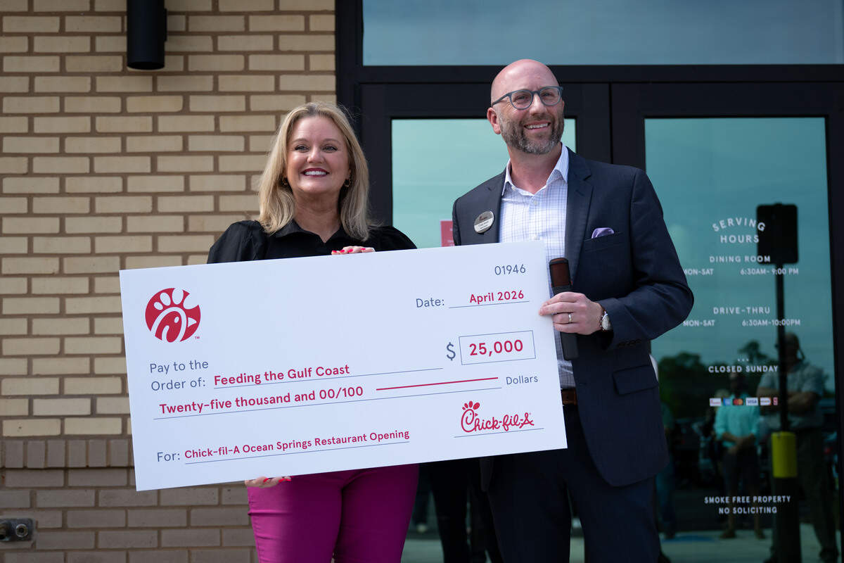 Feeding the Gulf Coast Vice President of Development and Marketing Cyndy Baggett, left, holds a check for $25,000 with Owner-operator Craig Smith during a ribbon-cutting ceremony for a new Chick-fil-A in Ocean Springs.