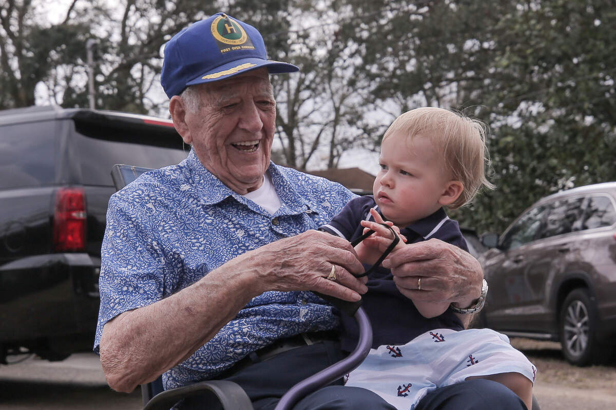 George Roberts holds his 19-month-old great-grandson, George, during his 100th birthday party at his home in Gulfport, Miss., Feb. 28, 2021. “My namesake,” Roberts said.