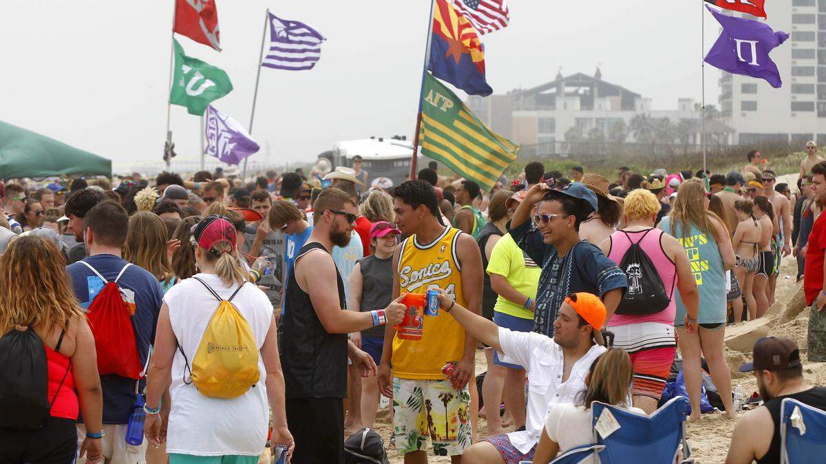 NATHAN LAMBRECHT/THE MONTIOR VIA ASSOCIATED PRESSSpring-breakers sit on the beach under flags from their universities March 17 at South Padre Island, Texas.