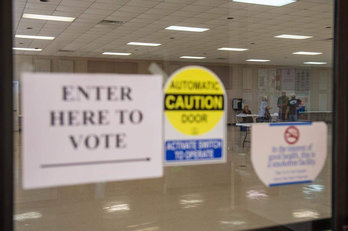 Voters talk with election workers at the St. Martin Community Center in St. Martin on Tuesday, June 7, 2022.