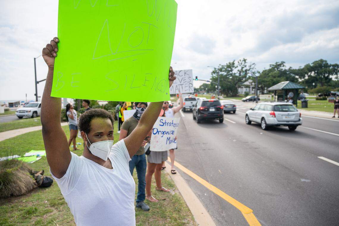 A protester holds a sign that reads “We will not be silenced.”