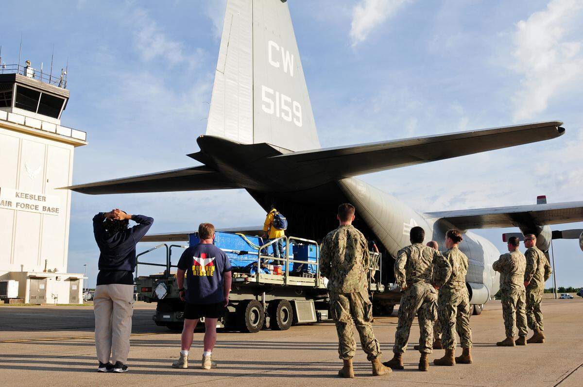 Seabees assigned to Naval Construction Group 2 and members from the Institute of Marine Mammals Studies watch as U.S. Naval Marine Mammal Program officials push dolphin tanks onto a K-loader to transport the dolphins to IMMS. Navy program handlers and veterinary personnel transported three dolphins from the Navy’s facilities at the Naval Warfare Systems Center Pacific in San Diego to Keesler to be loaned to IMMS for extend breeding and studies to further marine mammal science. IMMS is a research and rehabilitation facility that is known for providing care to stranded animals.