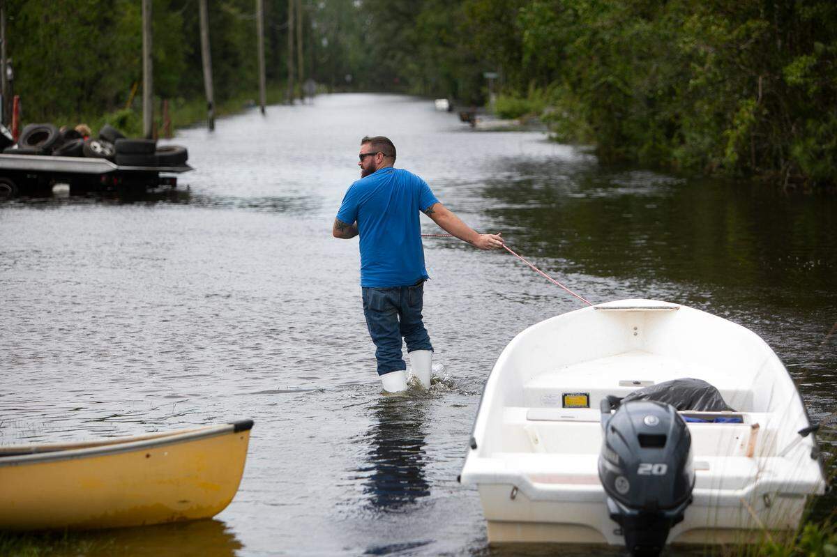 A man pulls a boat down a flooded street in the Shoreline Park community of Bay St. Louis after Hurricane Ida on Aug. 30, 2021.