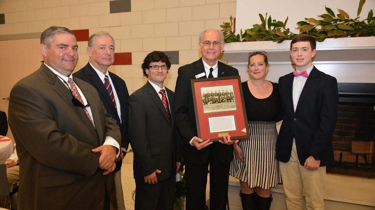 RICHARD GLEBER/ST. STANISLAUS COLLEGE 
 Brother Francis David, President of Saint Stanislaus College (third from right) presents the Glover family the framed portrait of Harry C. 'Wop' Glover, Jr. Attending were (from left) great nephew Troy Campbell, nephew Doug Campbell, Alumni Association President Patrick Martinez, Brother Francis David, great niece Aimee Ladner and great-great-nephew Luke Ladner.