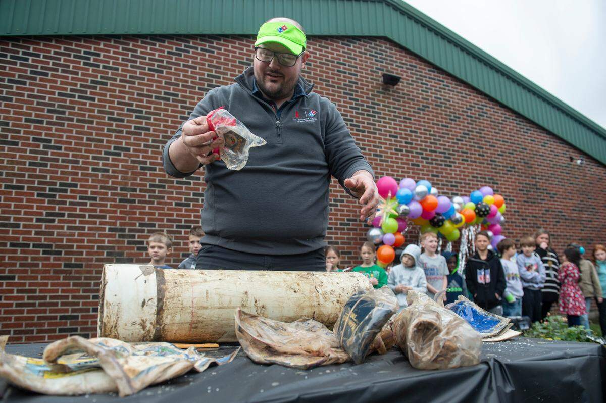 Colby Holland, a former student at W. J. Quarles Elementary in Long Beach, pulls out Pokemon cards from a time capsule on Friday, Dec. 13, 2024, that he and his classmates buried in 1999.