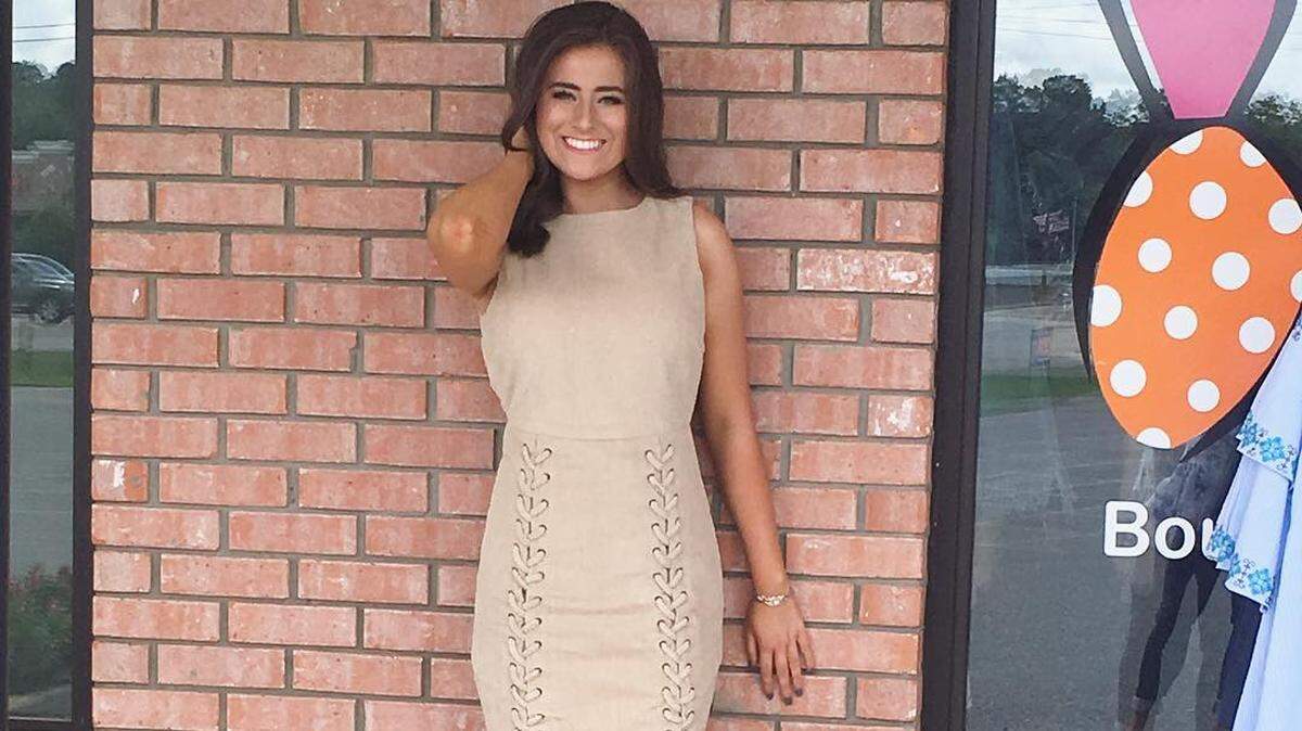 Holly Brand models a beige corduroy dress in front of her store, Brand New You.