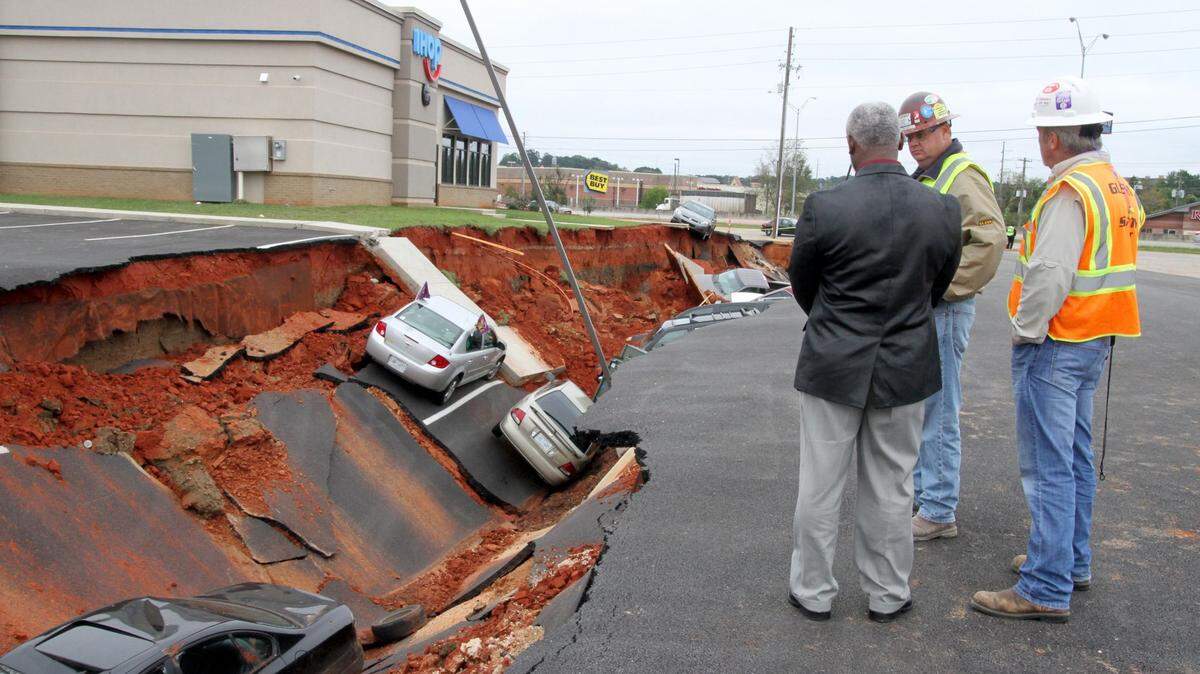City of Meridian Public Works Director Hugh Smith and members of a crew with Glenn's Cranes of Meridian discuss ways to remove cars from a cave-in in the parking lot of an IHOP restaurant, Monday, Nov. 9, 2015. Engineers are trying to determine what caused a drainage structure to collapse beneath the parking lot of the new restaurant, opening a gap that swallowed at least 14 vehicles, a mayor in eastern Mississippi said Monday. (Paula Merritt/The Meridian Star via AP)