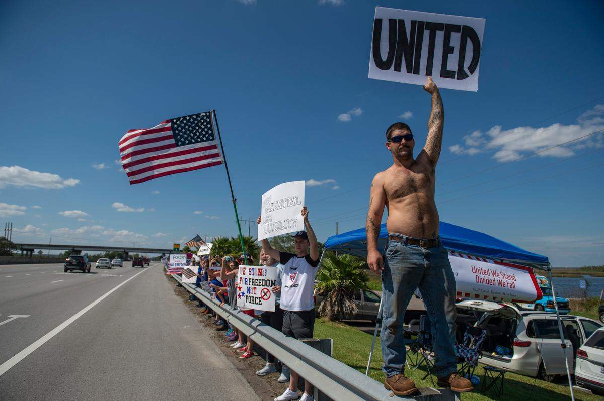 Protestors wave flags and signs on the side of Highway 90 during a protest against Ingalls’ vaccine mandate in Pascagoula on Friday, Oct. 8, 2021.