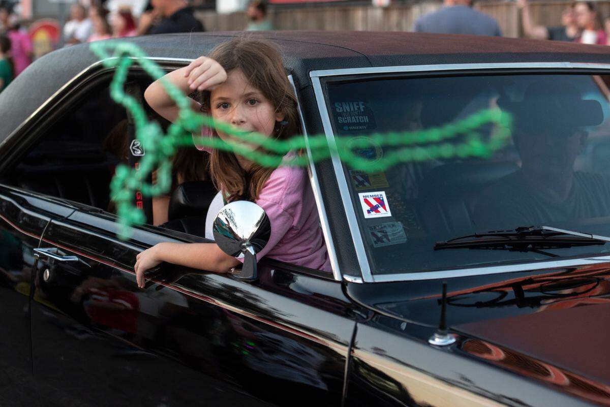 A girl throws beads from a Cruisin’ vehicle during the Long Beach Parade in Long Beach, one of the events in Cruisin’ The Coast, in 2024.