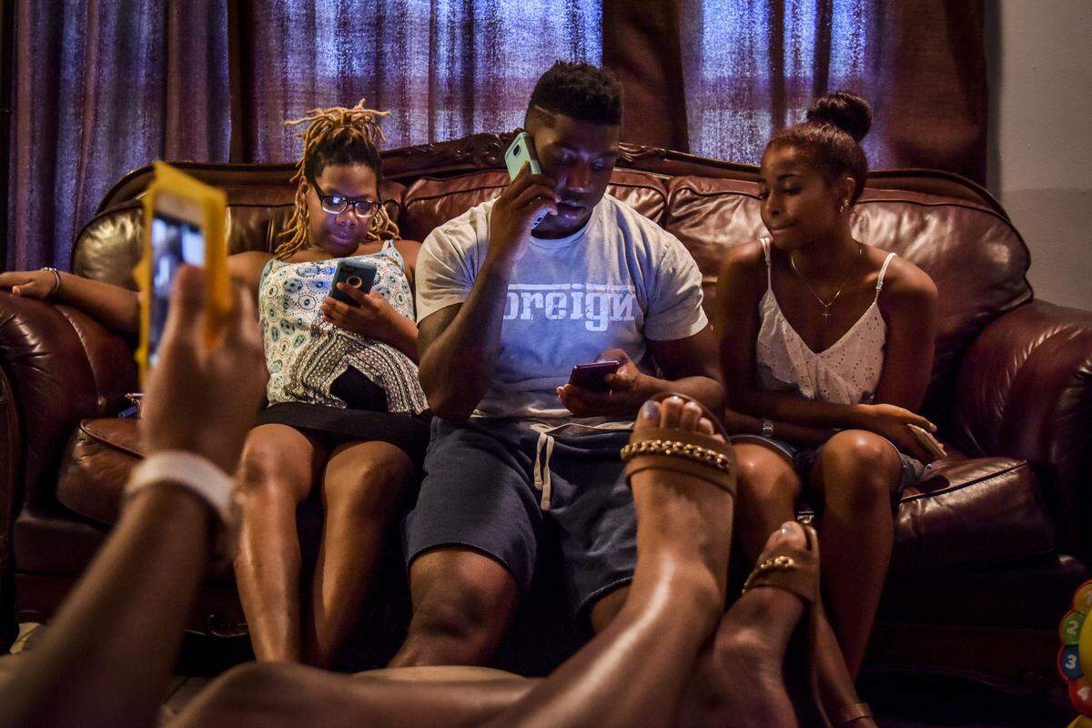 Ronnie Jackson - flanked by his pregnant sister, Jasmine Jackson, left, and his girlfriend, Madelyn Duronslet - takes a phone call at home.