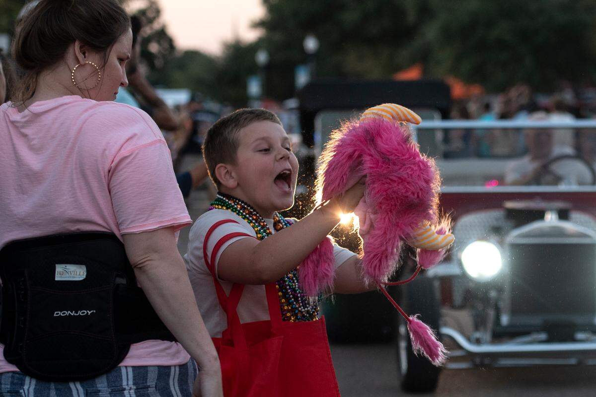 A spectator catches a toy during the Long Beach Parade during Cruisin’ The Coast 2024.
