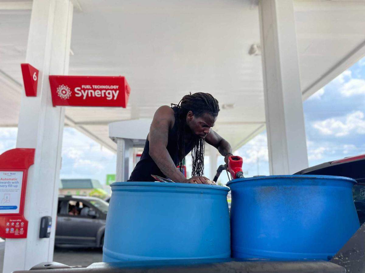 Louis Robinson of New Orleans fills up multiple gallon drums with gasoline at an Exxon station on U.S. 49. He is bringing fuel back to the city and his neighborhood in the 7th ward.