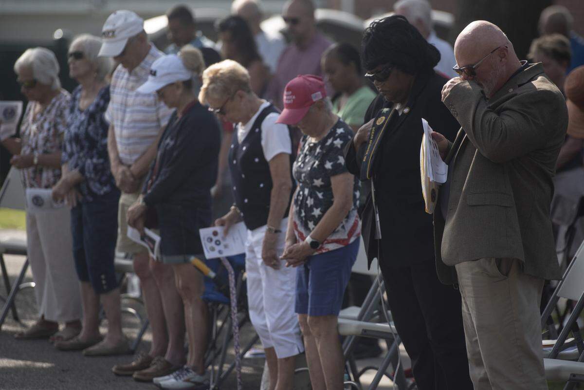 Veterans and members of the public pray during a Memorial Day ceremony at Biloxi National Cemetery in Biloxi on Monday, May 26, 2025.