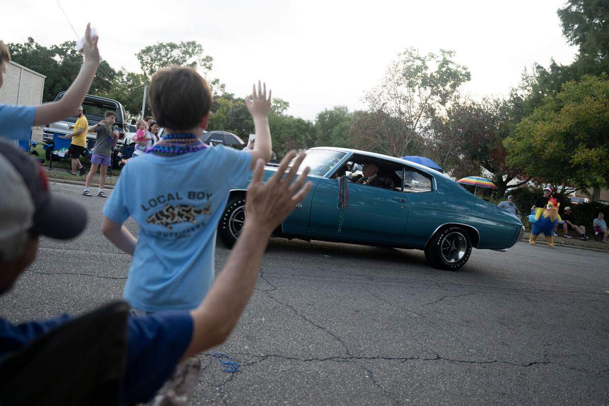 Event bystanders wave Monday as vintage cars pass by during the Long Beach Cruisin’ The Coast Parade.
