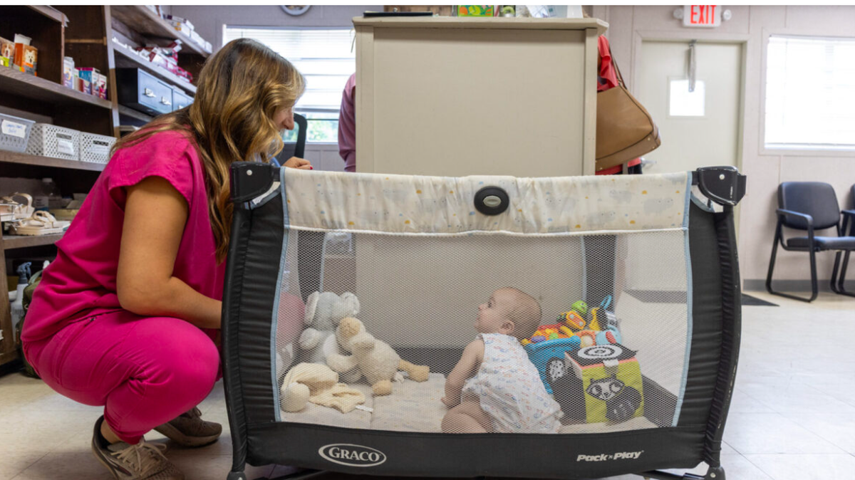Marla Demita watches her 10-month-old son, Dean Demita, in his playpen at Yazoo City Animal Hospital, Thursday, June 12, 2025, in Yazoo City, Miss. Credit: Eric Shelton/Mississippi Today
