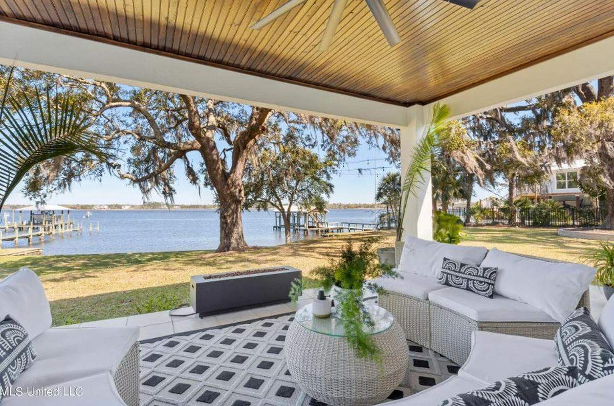 The patio with its fire feature looks out over the Back Bay in Biloxi and the acre yard with old oak trees.