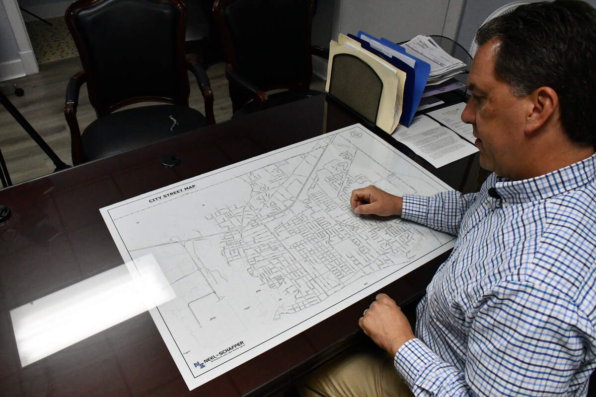 Pascagoula City Manager Justin Larsen reviews a city map while discussing drainage patterns and planned infrastructure improvements aimed at reducing flooding near Market Street and U.S. 90.