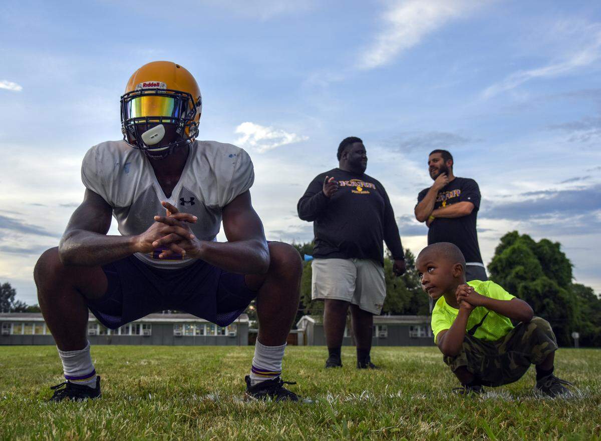 Three-year-old Liam Randall keeps an eye on Ronnie Jackson during drills before practice. Liam is the son of the team’s outside linebackers coach, Norman Randall. Head coach Brice Brown chats with offensive line coach Chris DeGiovanni in the background.