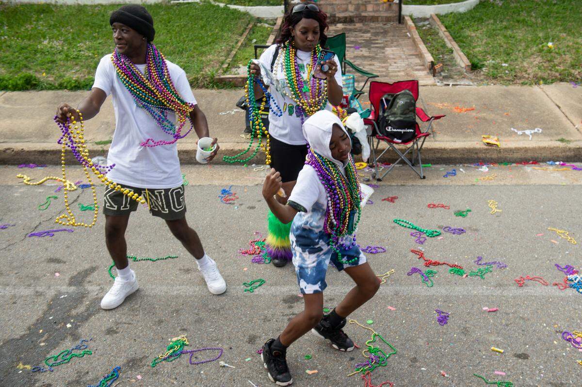 Paradegoers dance as they collect beads during the Gulf Coast Carnival Association Mardi Gras parade in Biloxi on Tuesday, Feb. 21, 2023.