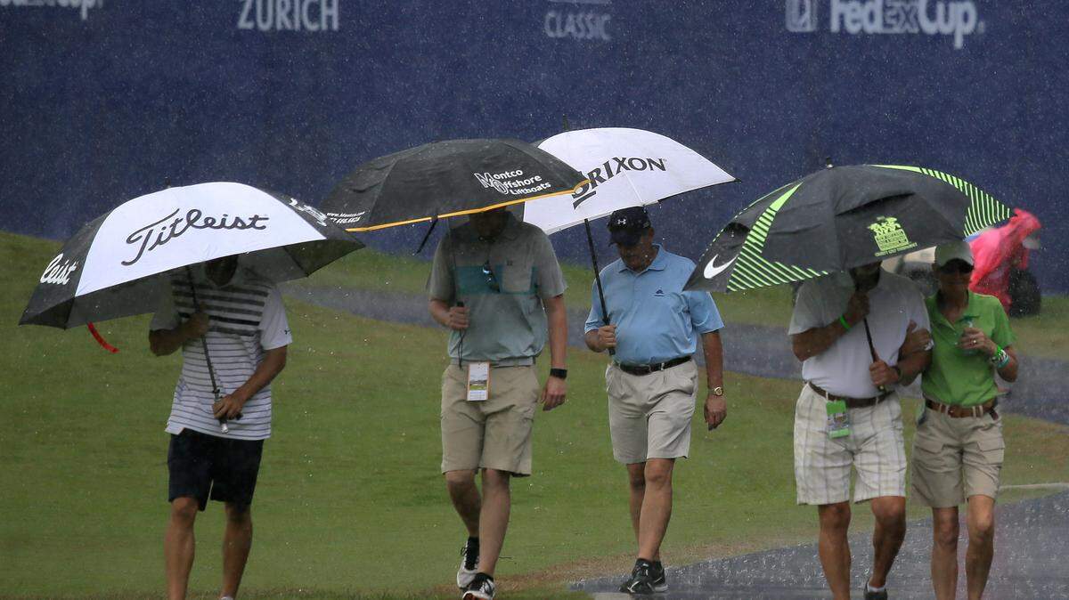 DAVID GRUNFELD/ASSOCIATED PRESS 
 People leave the course in the rain during the first round of the Zurich Classic golf tournament in Avondale, La., Thursday.