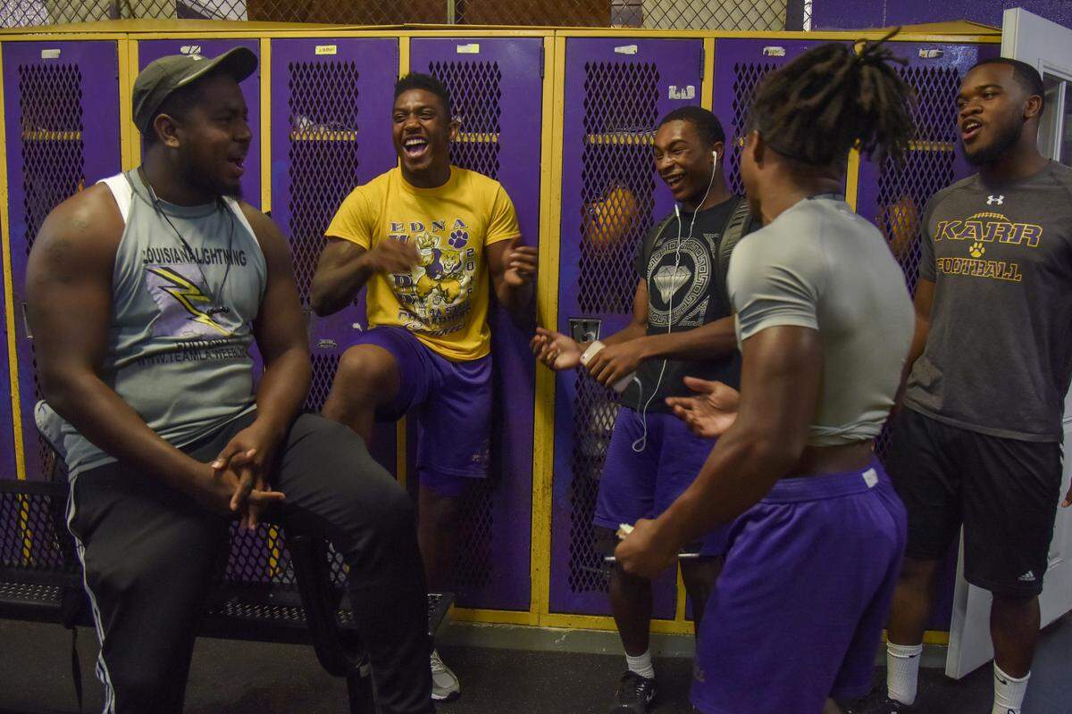 Edna Karr’s Ronnie Jackson, second from left, shares a laugh with linebackers coach Girard Hawkins, left, and fellow players (from left to right) Leonte Richardson, Lonte Nettles and Devin Bush before practice.