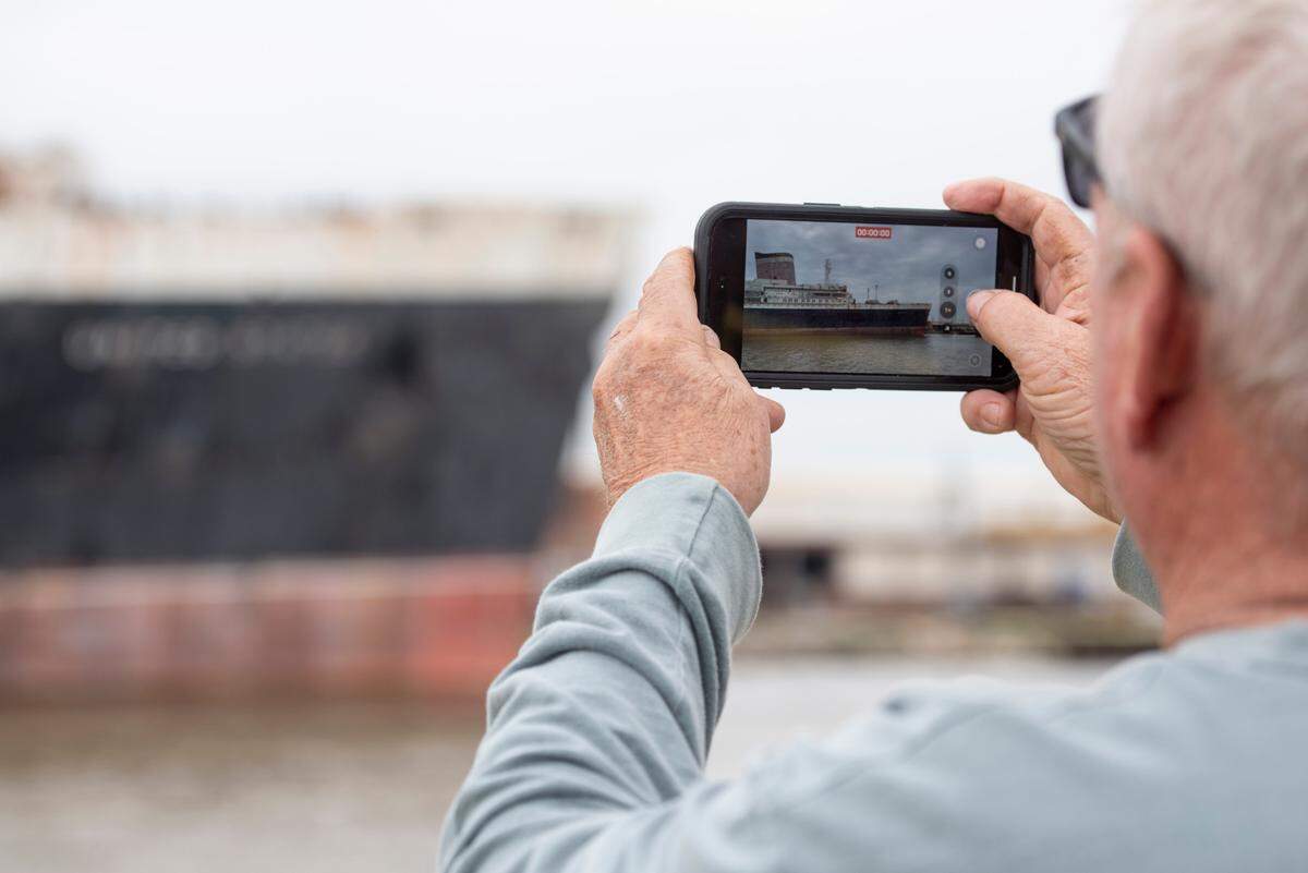Passengers on The Perdido Queen take photos of the SS United States as it is docked in Mobile on Friday, March 28, 2025.