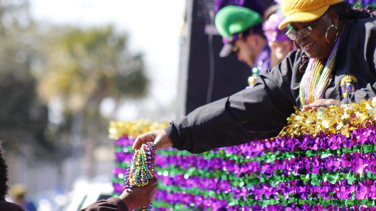 WESLEY MULLER/SUN HERALDA float rider hands beads to a reveler during Biloxi's Second Liners parade Saturday, Jan. 24, 2016.