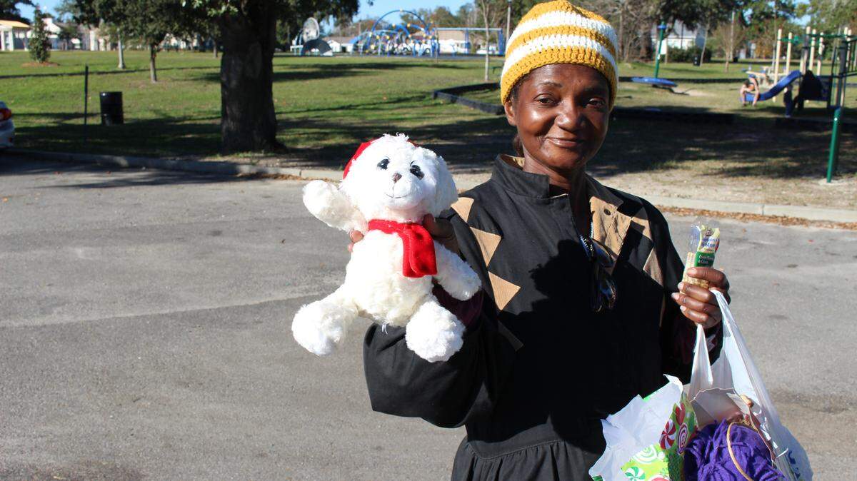 JEFF CLARK/SUN HERALDAntoinette Hughes shows off a teddy bear she got at Westide Park in Gulfport on Saturday during Shepherd of the Gulf's Christmas giveaway for homeless campers.