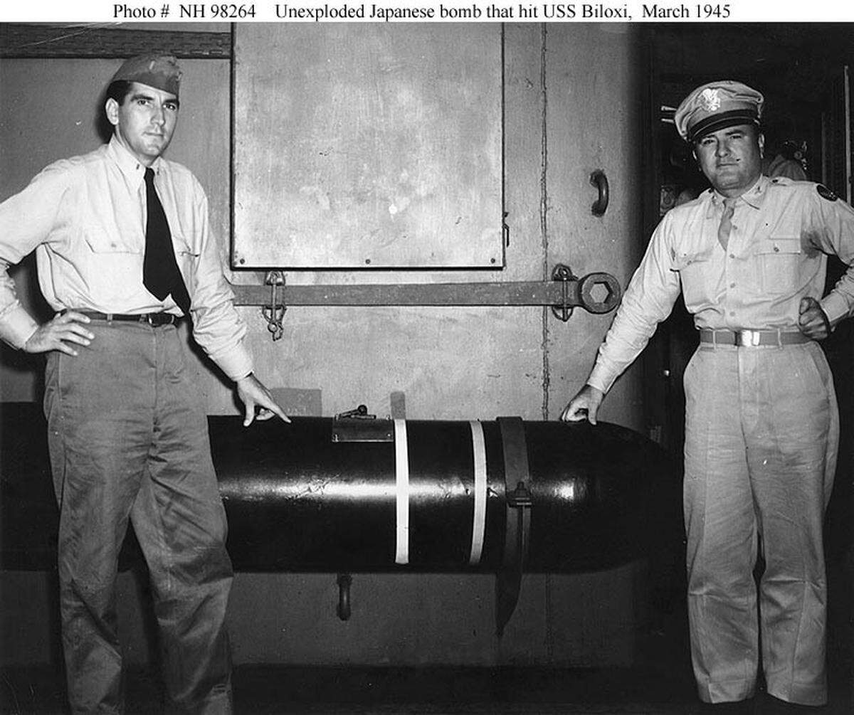 Major Anthony V. Ragusin (right) of Biloxi, Miss., and Ensign Jack Fisher, USNR, of Natchitoches, La. stand next to a 1,000 pound bomb that failed to detonate against the USS Biloxi after a Kamikaze slammed into its side off the coast of Okinawa on March 27, 1945.