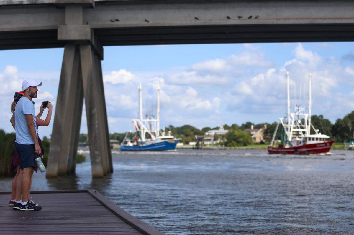 Spectators watch as shrimp boats line up at the Popps Ferry Bridge in Biloxi to dock in the back bay after a mandatory evacuation of local marinas and harbors. Sally is expected to bring high storm surge as the hurricane makes its way towards the Mississippi Coast.
