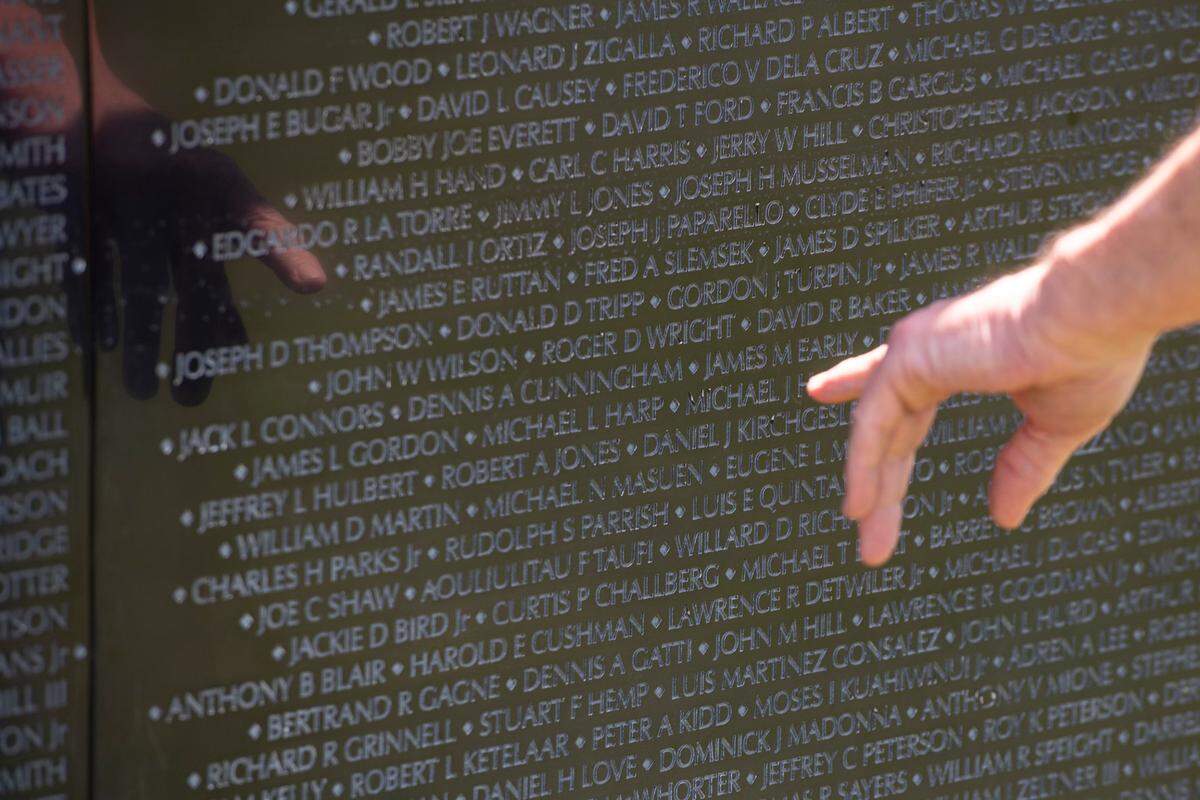 Visitors look at names on The Wall That Heals, a traveling three-quarter scale replica of the Vietnam Veterans Memorial in D.C., while it is on display at the D’Iberville Sports Complex in D’Iberville on Thursday, April 10, 2025.