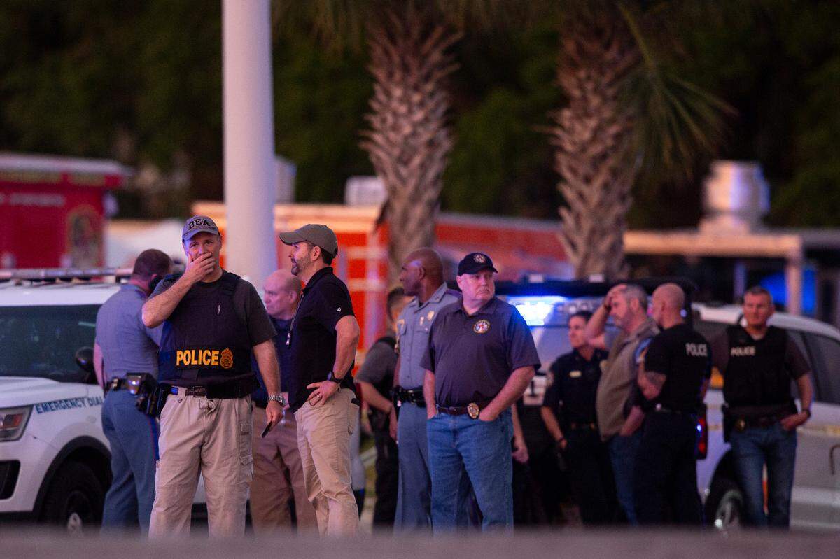 Law enforcement officers stand outside Surf Style in Biloxi after a chaotic shooting during Black Spring Break that left one police officer injured on Sunday, April 16, 2023.