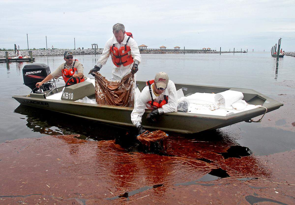 Workers skim a patch of weathered oil near a boat ramp in Gulfport, Mississippi, in July 2010.