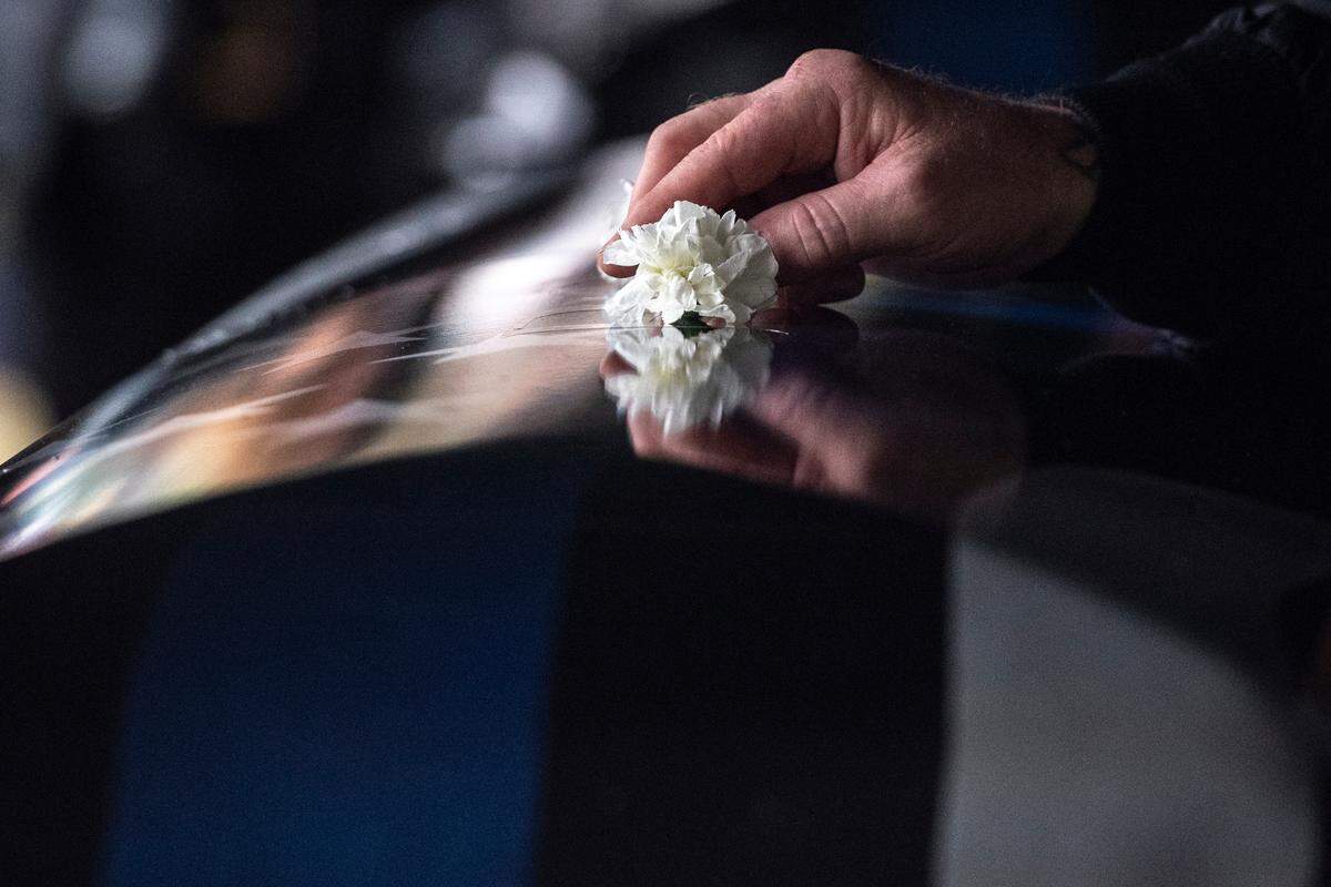 Mourners lay white flowers on the caskets of Bay St. Louis police officers Sgt. Steven Robin and Branden Estorffe at Gardens of Memory cemetery in Bay St. Louis on Wednesday, Dec. 21, 2022. Robin and Estorffe were killed responding to a call at a Motel 6 on Dec. 14.
