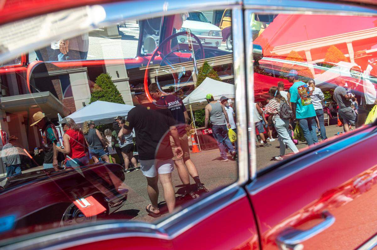 People looking at classic cars are reflected in the window of a car during Cruisin’ The Coast in 2022. For the first time in 17 years, Waveland will join the “Largest Block Party.”