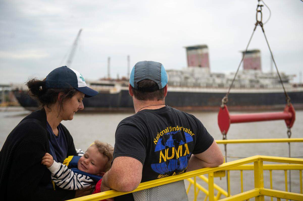 Passengers on The Perdido Queen look out at the SS United States in Mobile on Friday, March 28, 2025. The Perdido Queen is offering boat tours of the SS United States while it is docked in Mobile.