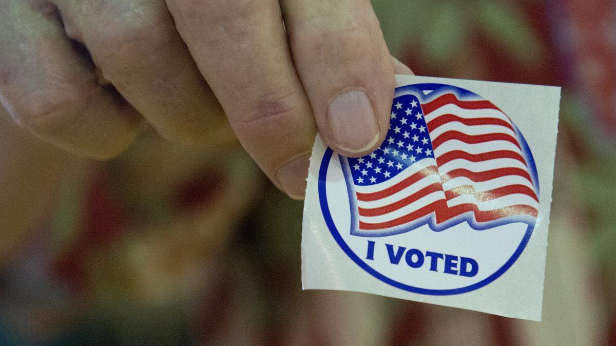 A poll worker holds up an election sticker at a polling location at Dr. Frank Gruich Sr. Community Center in Biloxi during the Mississippi Primary Election on Tuesday, Aug. 8, 2023.