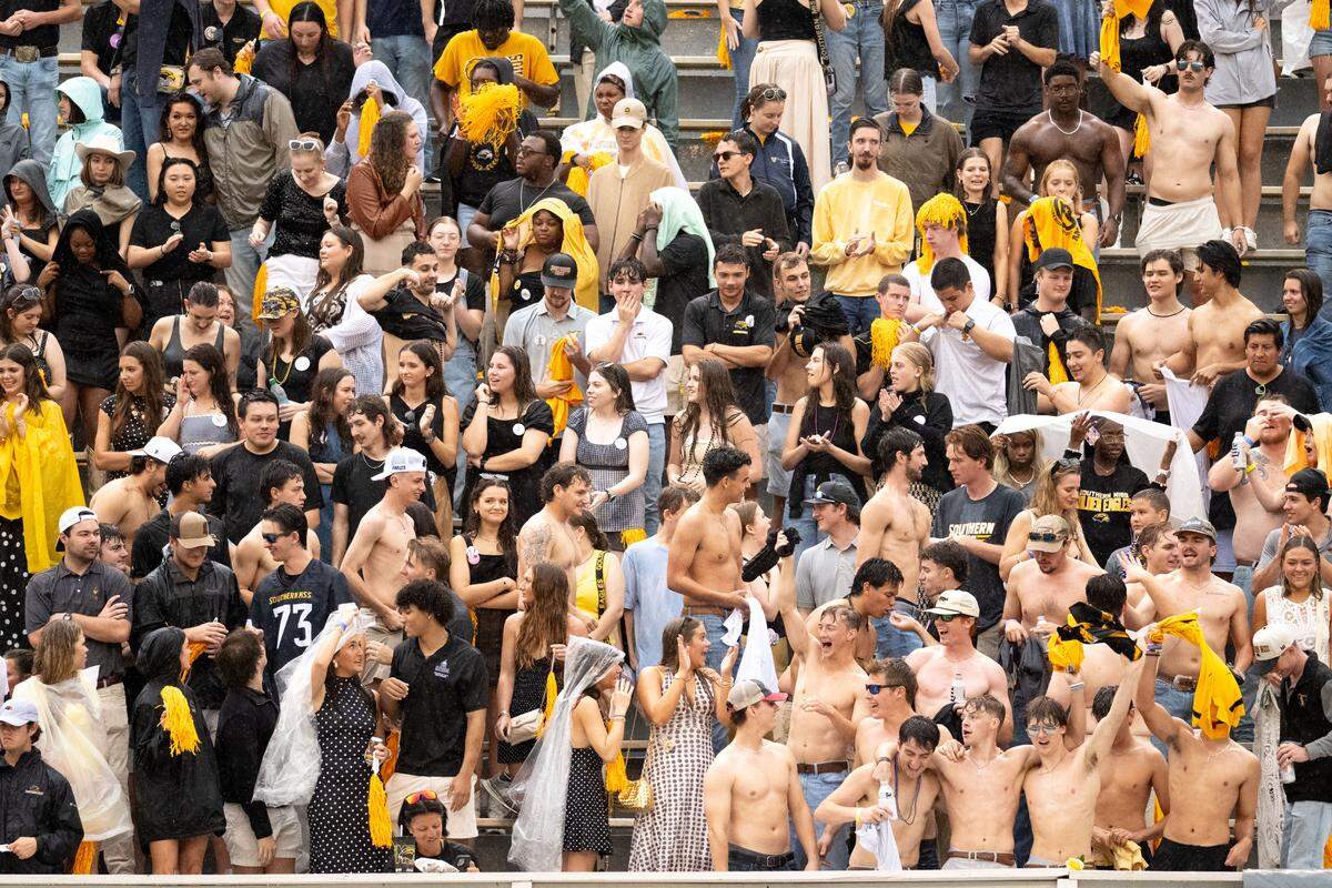 Southern Miss students take off their shirts in the rain as they cheer for their team.