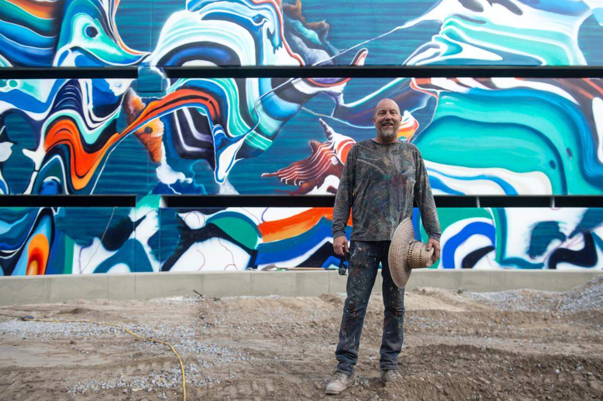 Artist Douglas Hoekzema, also known as Hoxxoh, poses in front of a mural he is painting on the parking garage at the new OS 1515 development in downtown Ocean Springs on Tuesday, Oct. 29, 2024.
