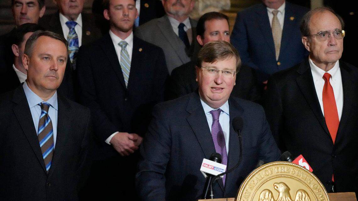 Mississippi Republican Gov. Tate Reeves, center, stands with House Speaker Jason White, R-West, left, and Republican Lt. Gov. Delbert Hosemann, right, as well as the legislators behind him, as he praises the passing of a state incentives package for a Mississippi factory that will manufacture batteries for electric vehicles.