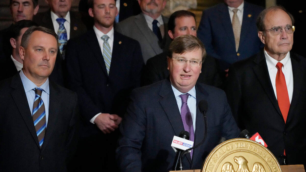 Mississippi Republican Gov. Tate Reeves, center, stands with House Speaker Jason White, R-West, left, and Republican Lt. Gov. Delbert Hosemann, right, as well as the legislators behind him, as he praises the passing of a state incentives package for a Mississippi factory that will manufacture batteries for electric vehicles.