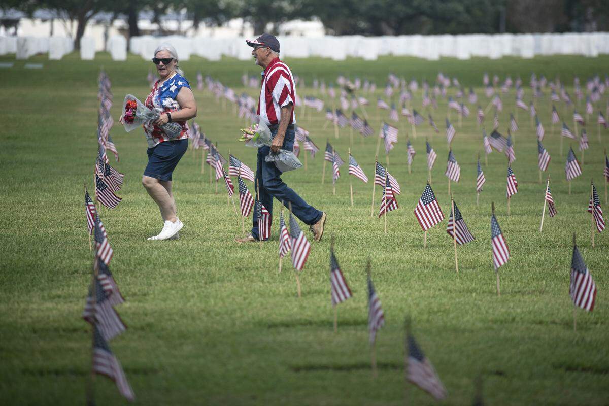 Families walk among the headstones at Biloxi National Cemetery in Biloxi during a Memorial Day ceremony on Monday, May 26, 2025.