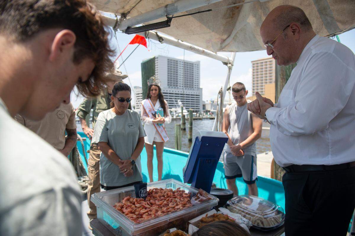 Msgr. Dominick Fullam, the pastor of St. Michael’s church in Biloxi, gives a blessing over the food during the Blessing of the Fleet on the water in Biloxi on Sunday, May 28, 2023.
