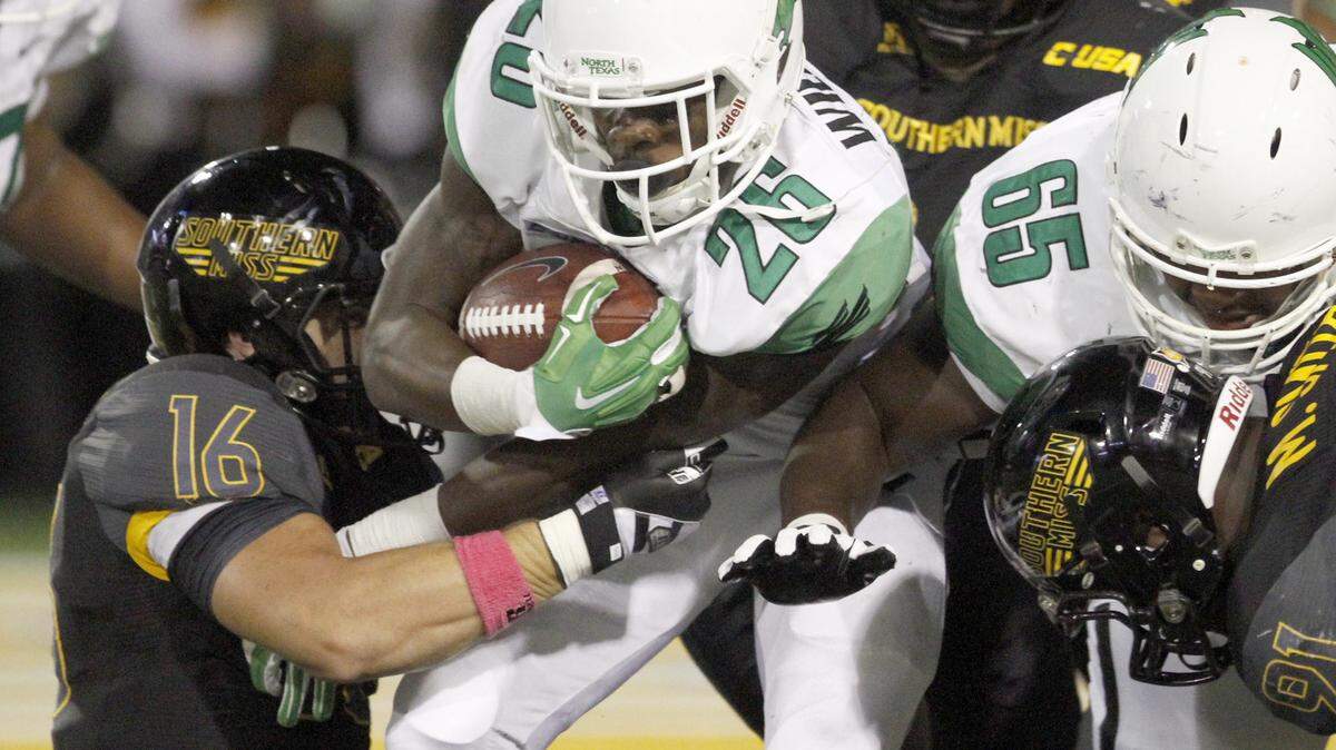 TIM ISBELL/SUN HERALD 
 North Texas running back Jeffrey Wilson is brought down by Southern Miss linebacker Elijah Parker in Hattiesburg on Oct. 3.