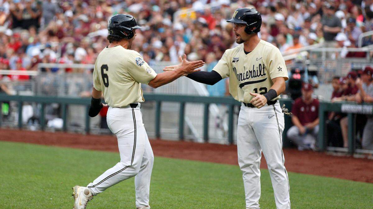Vanderbilt’s Tate Kolwyck, left, and Dominic Keegan, right, celebrate after scoring on a single by teammate CJ Rodriguez during the first inning against Mississippi State in Game 1 of the NCAA College World Series baseball finals, Monday, June 28, 2021, in Omaha, Neb. (AP Photo/Rebecca S. Gratz)