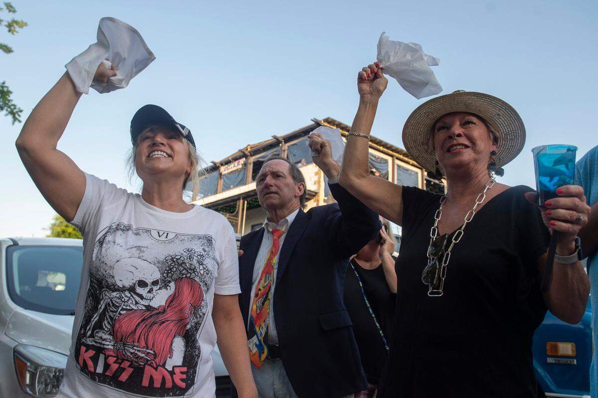Parade goers wave handkerchiefs during a second-line celebration for the life of Carl, a beloved rooster who was killed in April, in Ocean Springs on Tuesday, May 10, 2022.